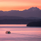 A Boat near a Shore with View of Mountains at Sunset logo