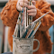 A Child Holding Paintbrushes in a Mug logo