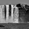 Grayscale Photography Of People Riding A Boat Near Waterfalls logo