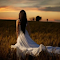 Woman in a White Dress Walking Through a Field at Sunset logo